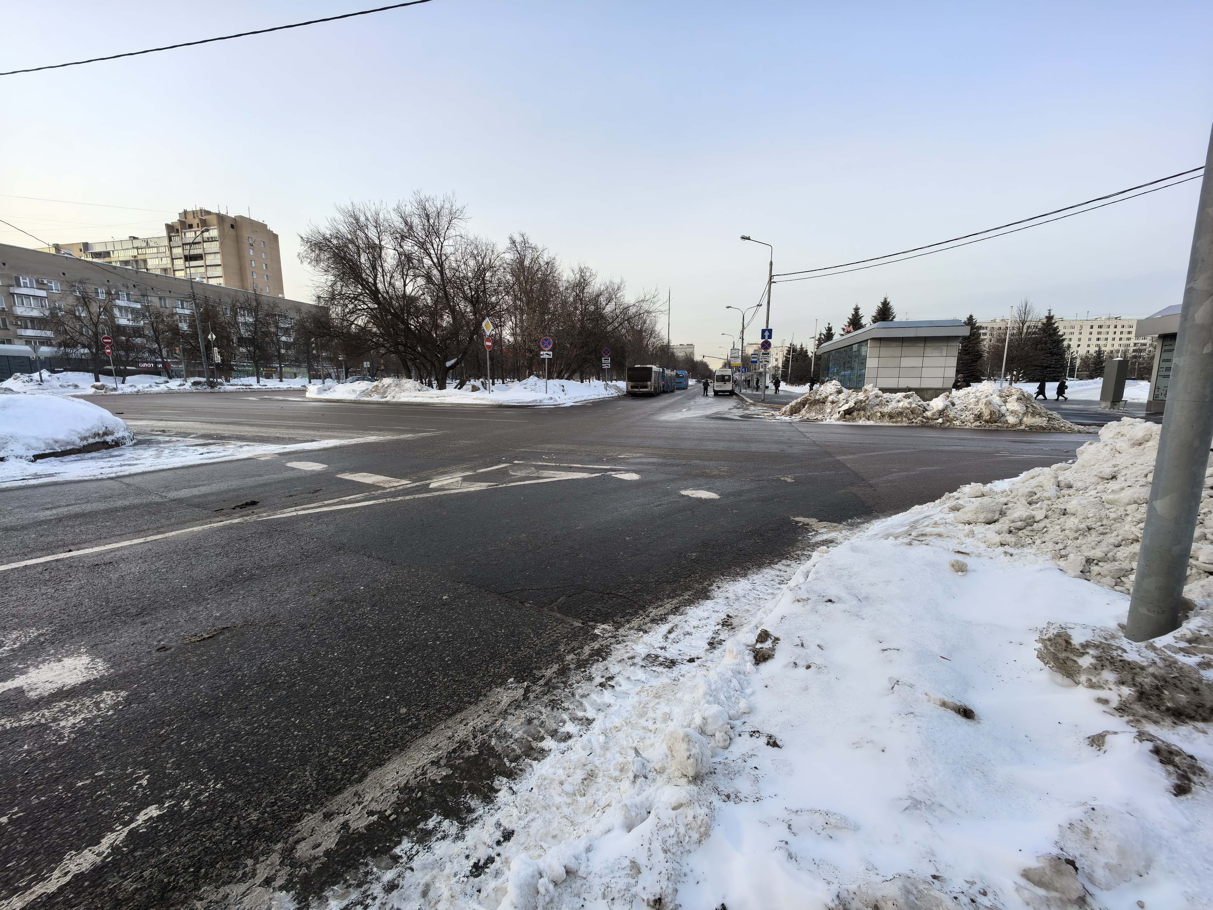 Городская проезжая часть с пешеходным переходом (зебра), зимнее время, видны автобусы и тротуары по бокам.