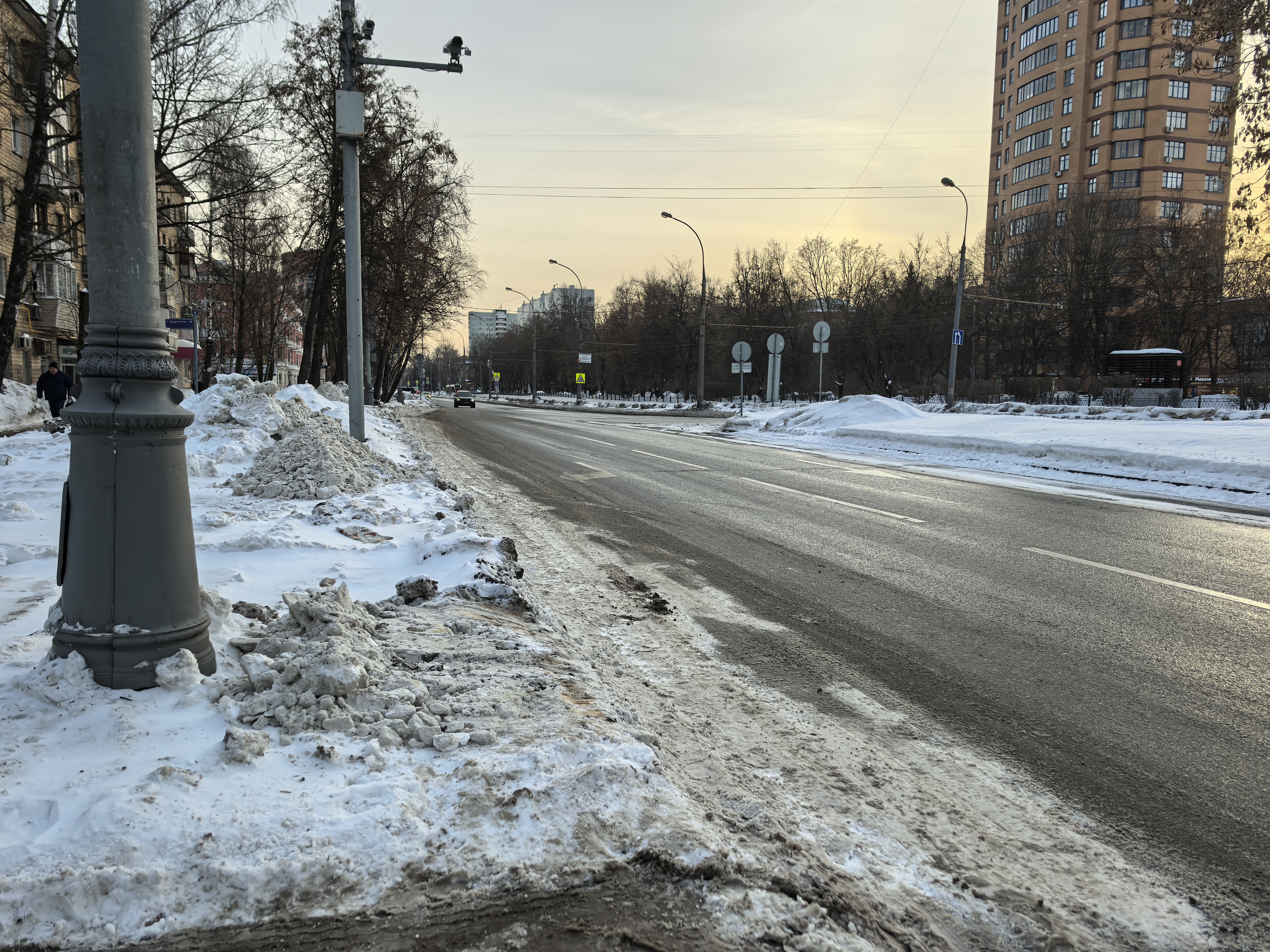 Городская проезжая часть с тротуаром, покрытым снегом. Пешеходный переход в видимой части отсутствует, движение осуществляется по проезжей части.