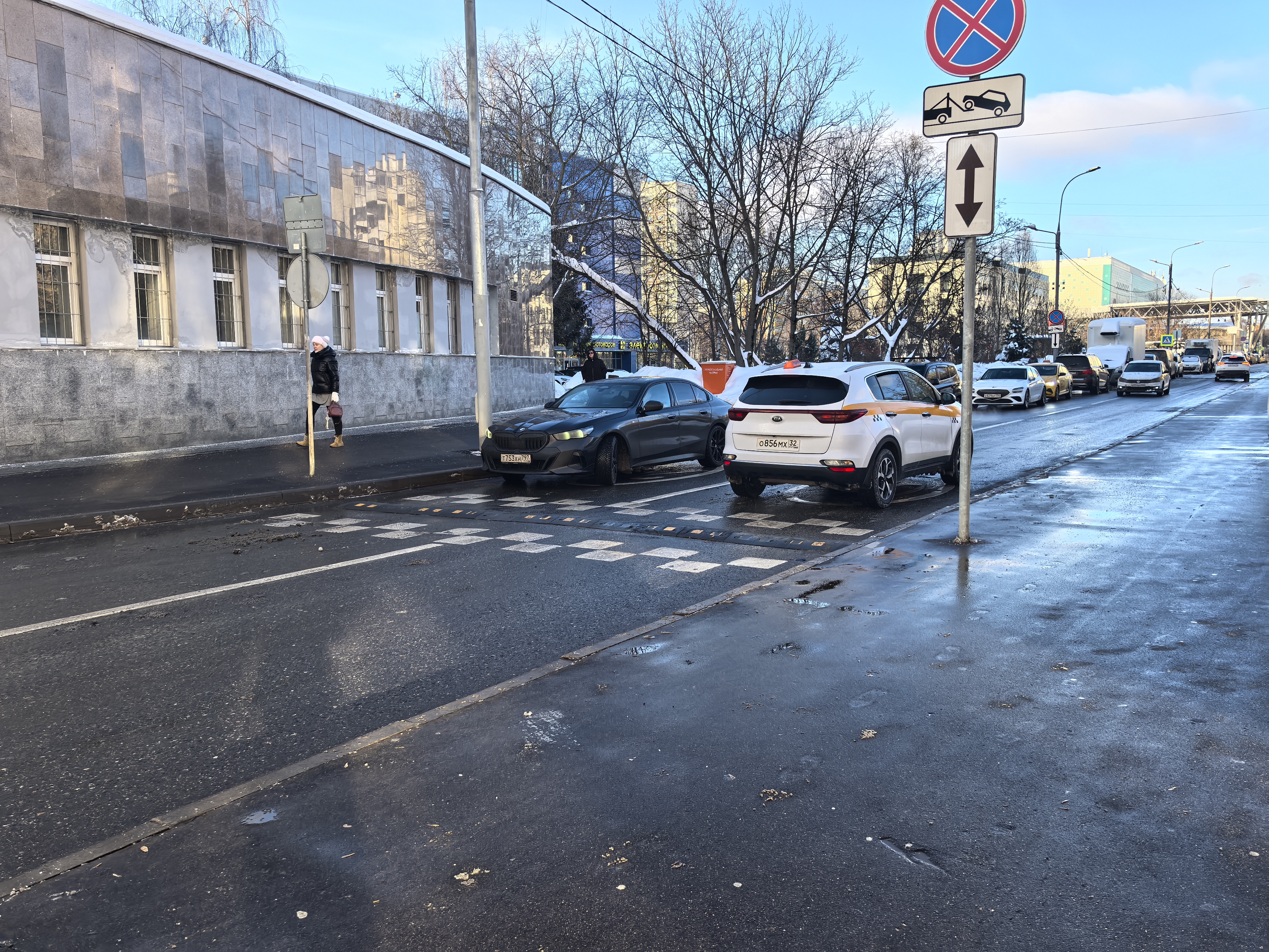 Участок городской дороги с пешеходным переходом (зебра) и лежачим полицейским. Видны припаркованные автомобили, частично перекрывающие переход.