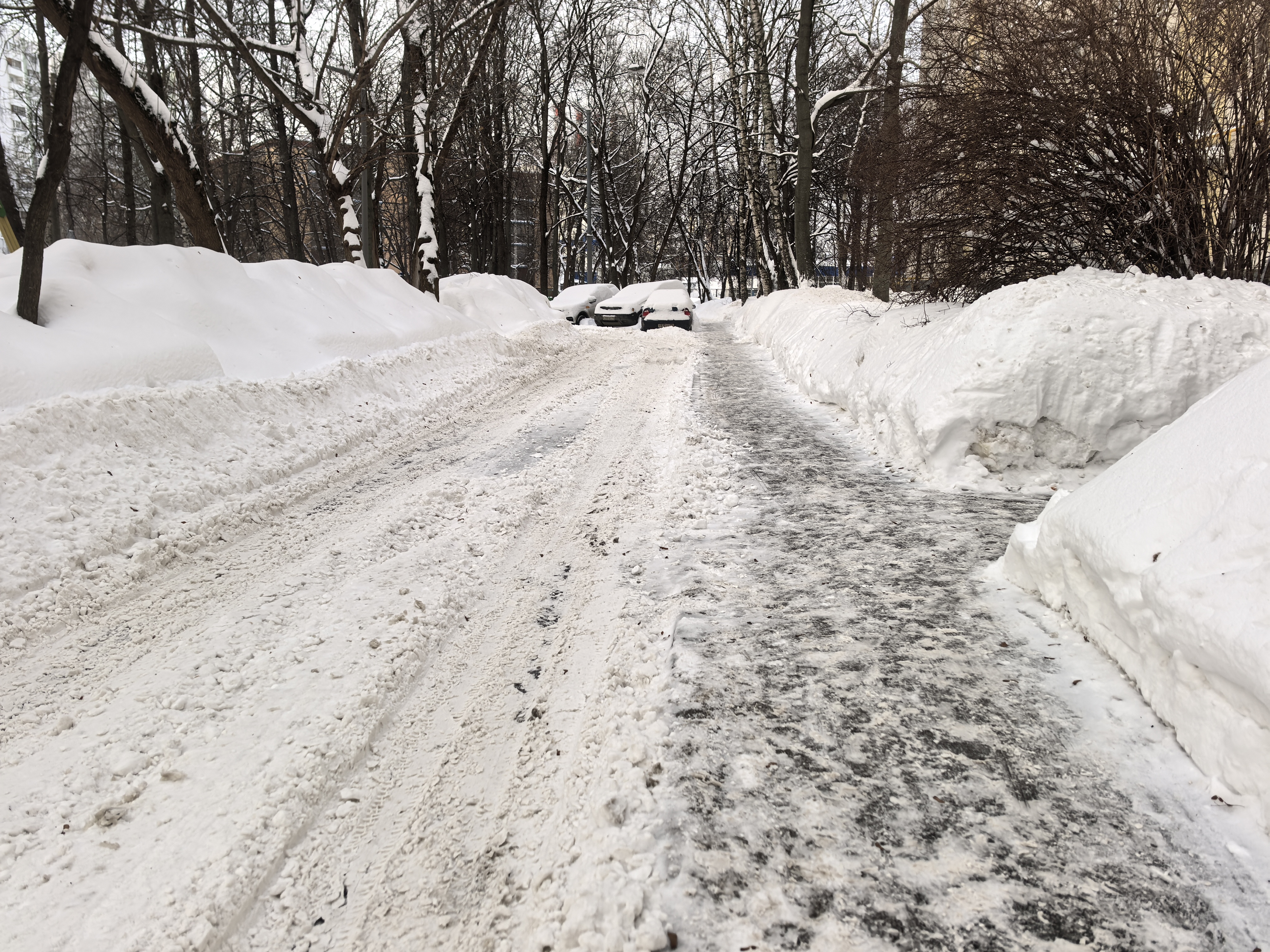 Дворовая территория, зимний период, дорога покрыта снегом и наледью, припаркованные автомобили, деревья по бокам