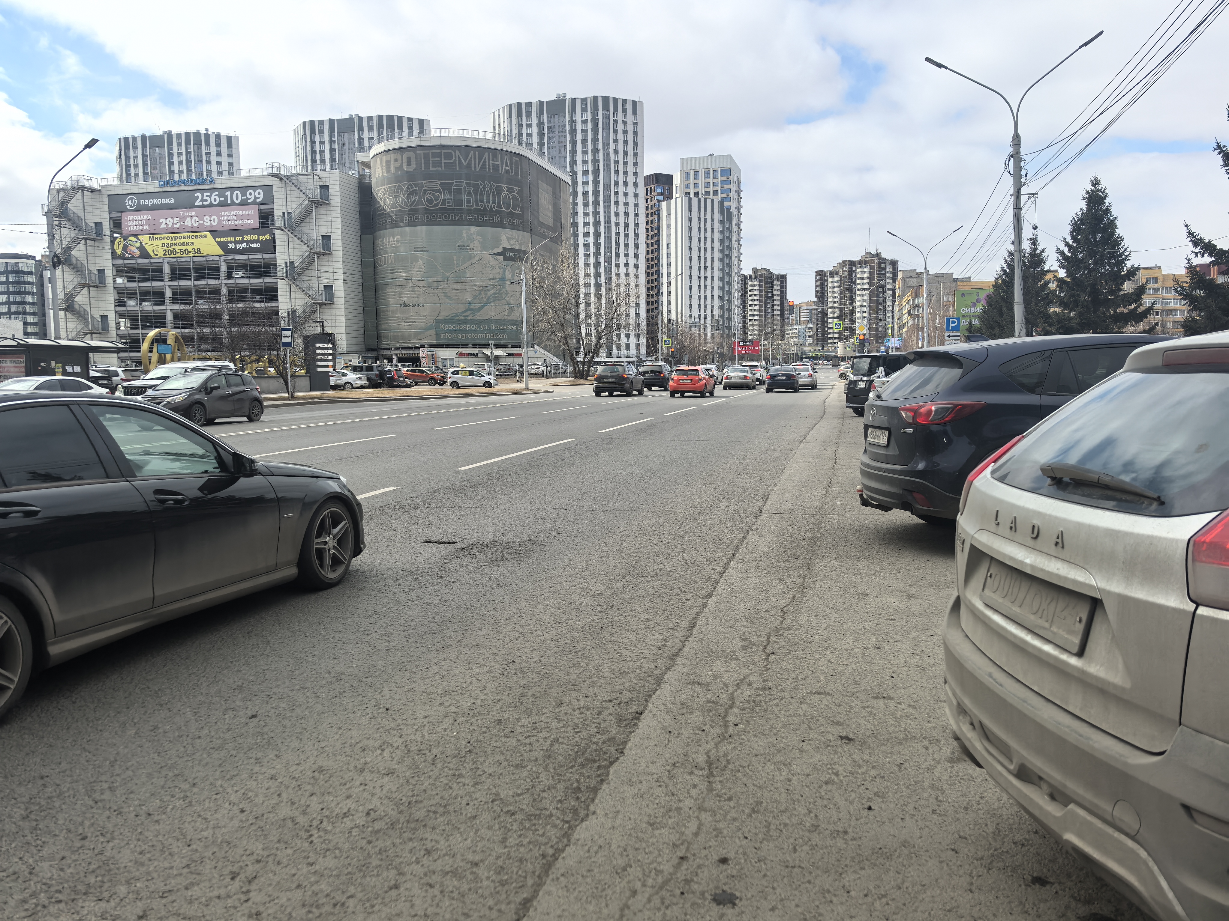 Широкая городская магистраль с интенсивным движением, оборудованная тротуаром и бордюром. Пешеходный переход в непосредственной близости от точки съемки отсутствует.